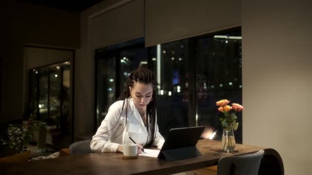 Dívka s dredy v bílé košili pomocí digitálního tabletu zařízení na online lekci, učí se z videa prostřednictvím tabletu. Koncept online učení. — Stock video