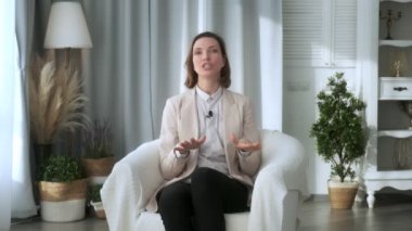 Gülümseyen genç kadın, blogger, vlogger, etkili, evde oturan, konuşan, kameraya bakan, konuşan, video konferansı yapan, bir yaşam tarzı video blogu kaydeden, evde görüntülü sohbet yapan
