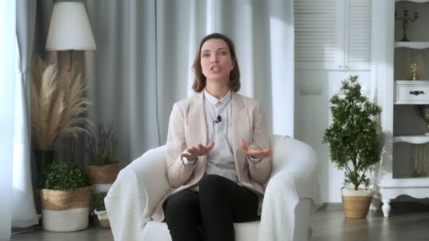 Mujer joven sonriente, blogger, vlogger, influencer, sentado en casa, hablando, mirando a la cámara, hablando, haciendo una videoconferencia, grabando un video blog de estilo de vida, haciendo un video chat en casa — Vídeos de Stock