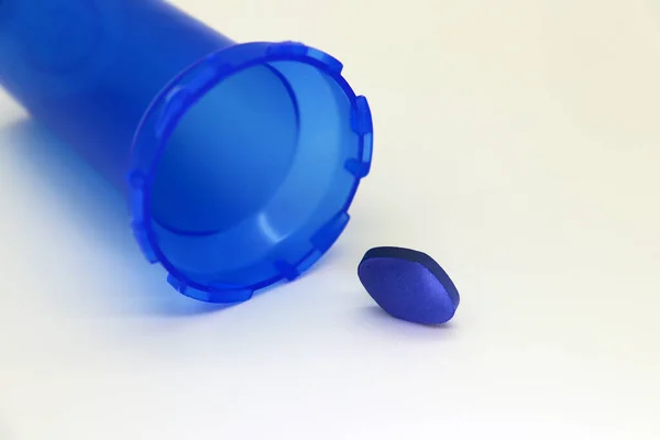 Little blue pill on white background with blue pill bottle