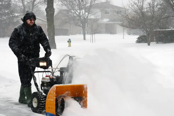 man clearing snow during heavy storm conditions in winter