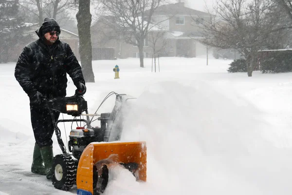 man clearing snow during heavy storm conditions in winter