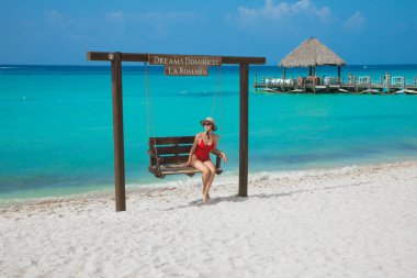 Kırmızı mayo giymiş, salıncakta sallanan genç bir kız.