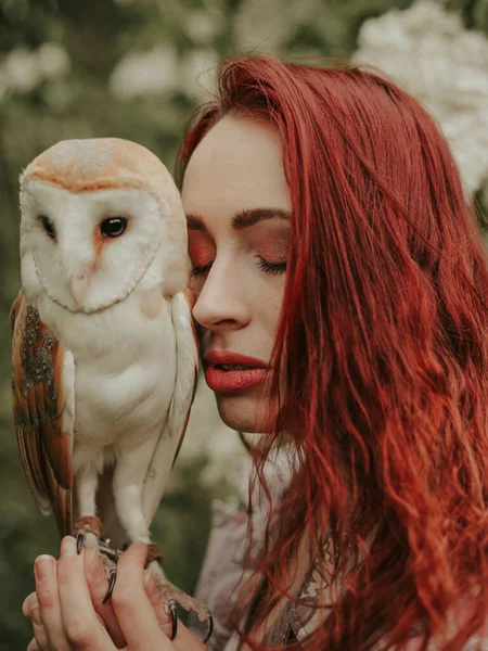 Baykuş ahırı baykuşuyla leylak bahçesinde kızıl saçlı genç bir kadının portresi.