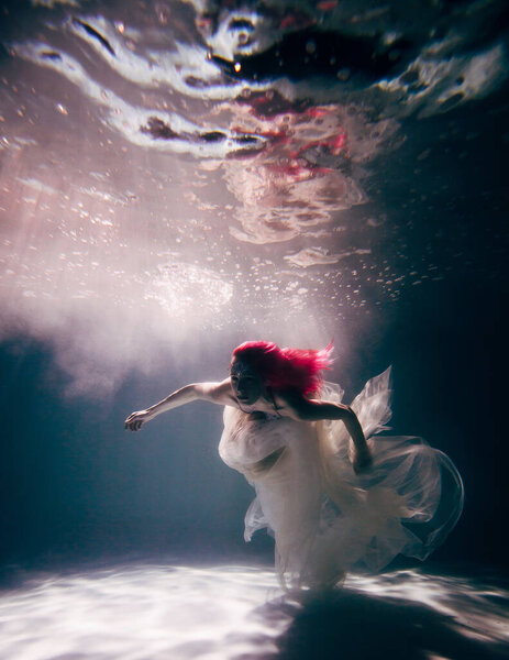 Young woman underwater in a beautiful dress underwater shooting