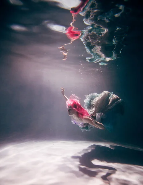 Young woman underwater in a beautiful dress underwater shooting