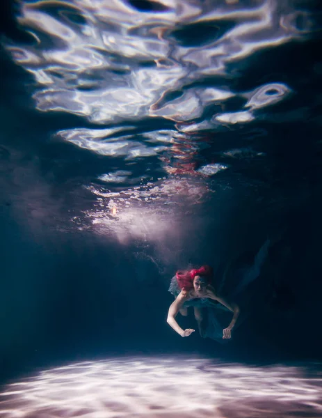 Young woman underwater in a beautiful dress underwater shooting