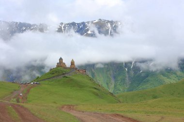 Kutsal Gergeti Trinity Kilisesi Gürcistan 'da bulutların içinde, arkasında dağlar olan Kafkaslar