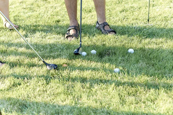 Golf topu, oyuncu bacakları, toplar ve golf sopaları.,