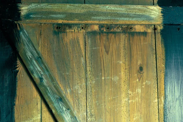 Eski tahtalar solucanlar tarafından hasar görmüş, yakından görülmüş, kapılar siyaha boyanmış, kalaslar birleşmiş.