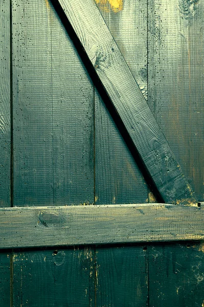 Eski tahtalar solucanlar tarafından hasar görmüş, yakından görülmüş, kapılar siyaha boyanmış, kalaslar birleşmiş.