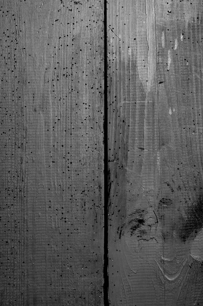 Eski tahtalar solucanlar tarafından hasar görmüş, yakından görülmüş, kapılar siyaha boyanmış, kalaslar birleşmiş.