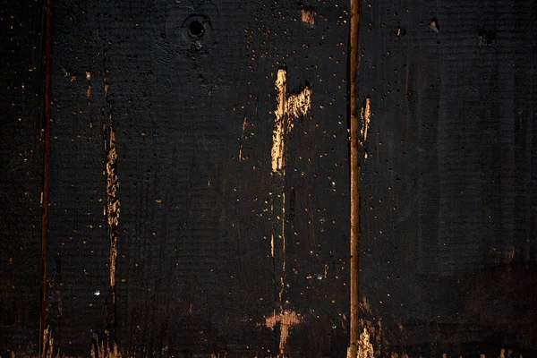 Eski tahtalar solucanlar tarafından hasar görmüş, yakından görülmüş, kapılar siyaha boyanmış, kalaslar birleşmiş.