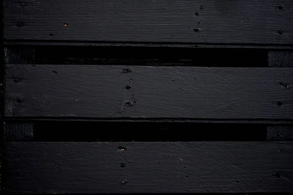 Eski tahtalar solucanlar tarafından hasar görmüş, yakından görülmüş, kapılar siyaha boyanmış, kalaslar birleşmiş.