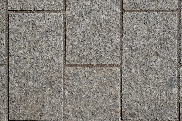 Rectangular gray cubes, equal sizes, straight, cut stones, edges on top, structure of split cubes, gaps between cubes with dark sand