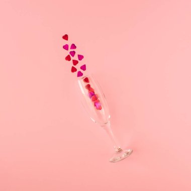 Pembe arka planda parlak kalp şeklinde parıldayan şampanya kadehinden yapılmış yaratıcı bir kompozisyon. Minimal Sevgililer Günü kutlama konsepti. Kırmızı ya da pembe estetik. Düz yatıyordu. Boşluğu kopyala.