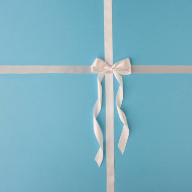 Mavi pastel arka planda beyaz saten kurdele. Minimum Noel, Sevgililer Günü hediye kartı fikri. Düz yatıyordu. Boşluğu kopyala.