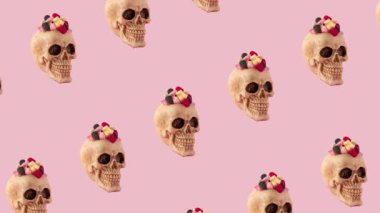 Creative 4k animation made of skull with candies on pink background. Pink Halloween motion background.