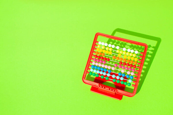 Minimal composition made of abacus on bright green backgrpund. Creative back to school concept.