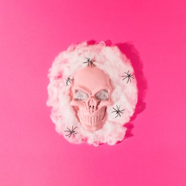 Örümcek ağındaki örümcekli kafatası canlı pembe arka plana karşı. En az Cadılar Bayramı ya da ölü konseptinin olduğu gün. Pembe estetik..