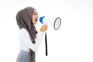 Young cute Muslim Arab woman wearing hijab speaking or shouting loud holding megaphone isolated on white background.