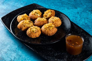 Pakistan baharatlı göl gappay, Hint pani puri ve Hint sokak yemeklerinin arka planında izole edilmiş mermer bir tabakta ekşi suyla dolu chaat masala fuşka.