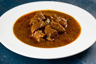 Pakistan ve Hint yemeklerinin arka planında mermer bir tabakta izole edilmiş baharatlı et qorma masala.