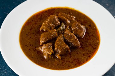 Pakistan ve Hint yemeklerinin arka planında mermer bir tabakta izole edilmiş baharatlı et qorma masala.