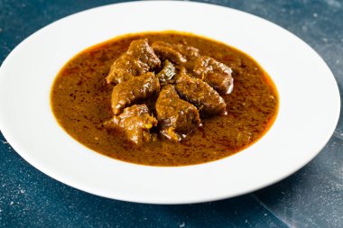 Pakistan ve Hint yemeklerinin arka planında mermer bir tabakta izole edilmiş baharatlı et qorma masala.