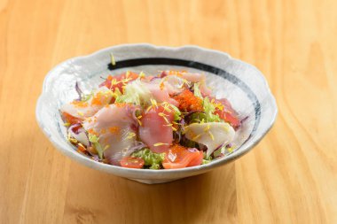 Japon yemeği stili taze Kaisen Salatası somon balığı dilimleri bir kâse içinde çiğ balıkla ahşap arka plan manzarası