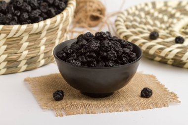 Kase içinde servis edilen kuru yaban mersini peçete tarafından izole edilmiş gri arka planda kuru meyveler.