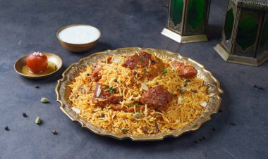 Hint baharatlı Biftek Biryani raita ve gulab jamun ile gri arka planda servis edilir.