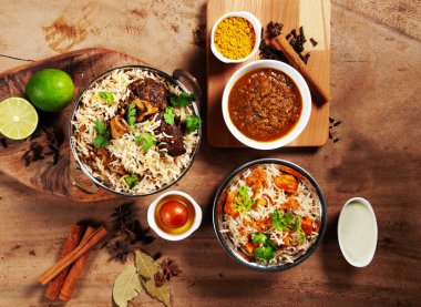 Hint baharatlı kuzu Shank Biryani, tereyağlı tavuk biryani soslu, limonlu raita ve gulab jamun gri arka planda servis ediliyor.