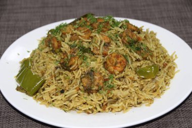 Karides Machbus veya karides biryani, ahşap arka planda izole edilmiş bir tabakta servis edilir.