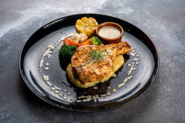 Tavada kurutulmuş somon, arka planda koyu renkli bir yiyecekle servis edilir.