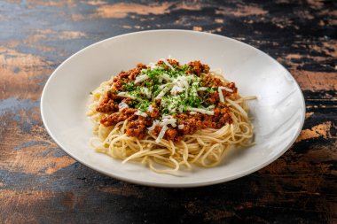 Spagetti soslu makarna koyu arka planda izole edilmiş bir tabakta servis edilir.