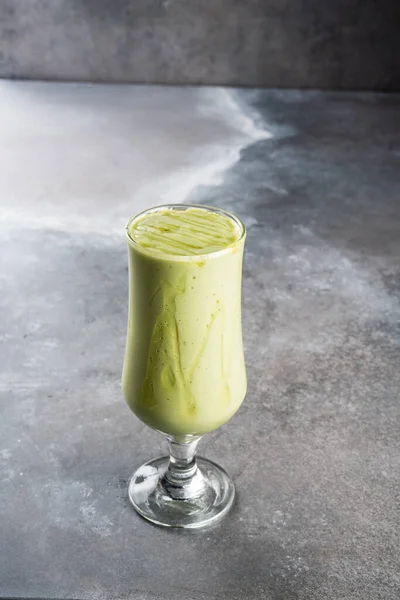 Fresh and healthy avocado juice served in glass isolated on dark background side view