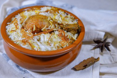 Raita ve turşulu tavuk biryani koyu arka planda izole edilmiş altın bir tabakta servis edilir.