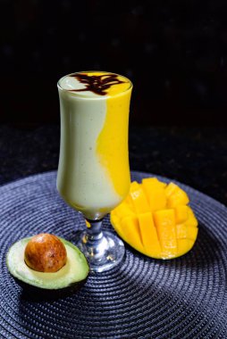 avokado ve mango karışımı koyu arka planda izole edilmiş bir tabakta servis edilir.