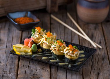 TAMAGO suşi rulosu, suşi rulosunun ahşap arka planında izole edilmiş bir kesme tahtasıyla servis edilir.