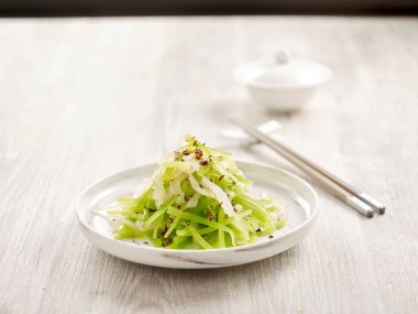 Scallion Yağı 'nda kuşkonmaz marullu dondurulmuş denizanası yemek çubuklarıyla gri arka planda izole edilmiş bir tabakta servis edilir.