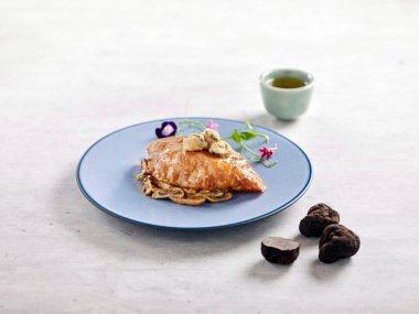 Tavada kızartılmış mantar soslu morina filetosu gri arka planda servis edilir.