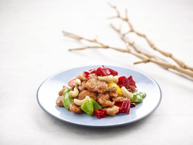 Sauteed Diced Mock Chicken with Dried Chilli and Cashew Nuts served in a dish isolated on wooden board side view on grey background