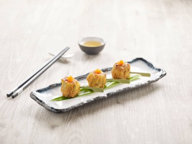 Kaz ciğeri soslu kızarmış Siew Mai gri arka planda, minder kenarında izole edilmiş bir tabakta servis edilir.