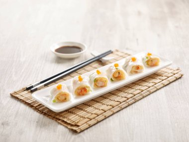 Haşlanmış pirinç rulosu ve çıtır karides tepside servis edilir yemek çubukları da gri mermer arka planda mat tarafında izole edilir.