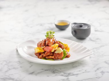 Pineapple 'lı tatlı ve ekşi domuz eti gri mermer arka planda servis edilir.