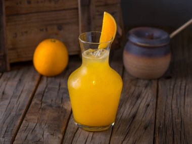 Çiğ portakal suyu ve çiğ portakal suyu. Ahşap masa manzarasında izole edilmiş bir kavanozda servis ediliyor.