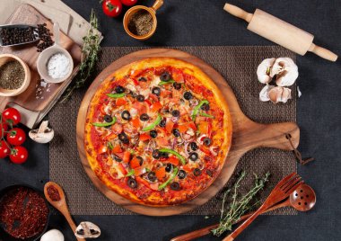 Domates, soğan, biber tozu, sarımsak ve karabiber içeren sebze aşığı pizzası ahşap masa üzerindeki ahşap kesim tahtası yan görüntüsü.