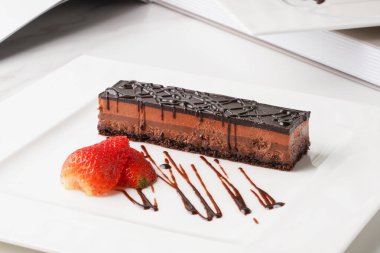 chocolate cake with strawberry served in a dish isolated on wooden table side view