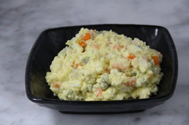 Olivieh Salatası gri arka plan görünümünde izole bir tabakta servis edilir